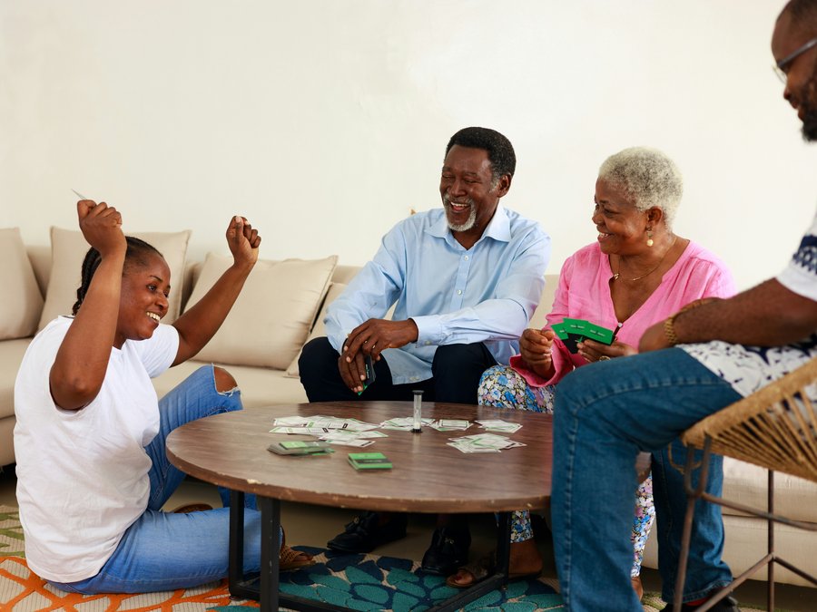 A family laughing together over a card game at home