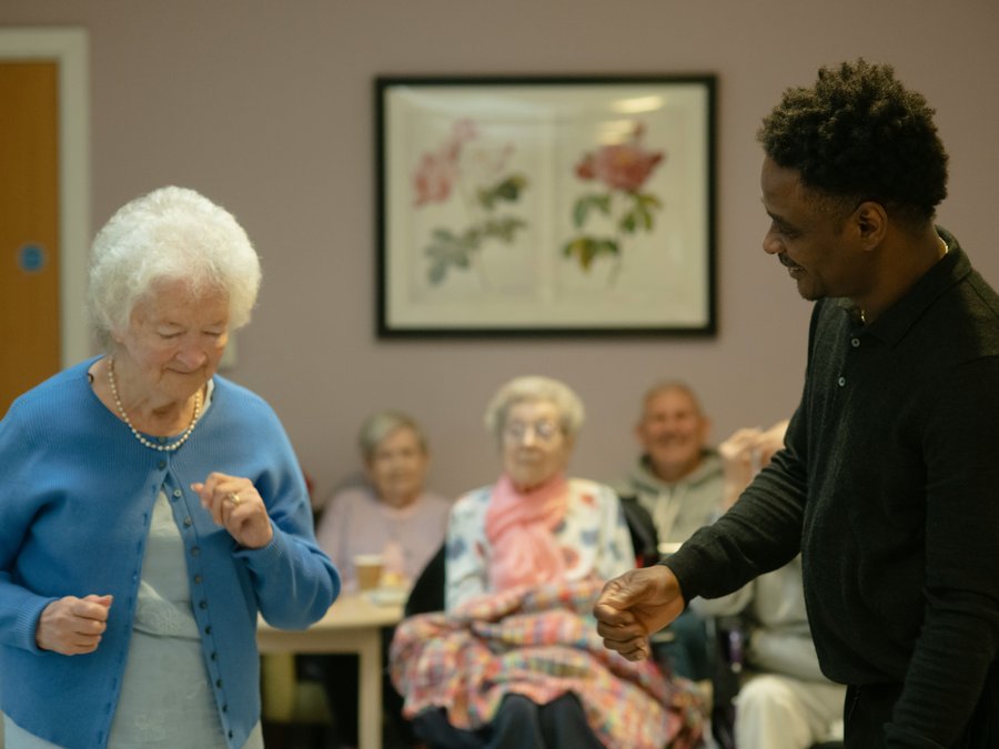 A carer dancing with a resident in a retirement estate day room