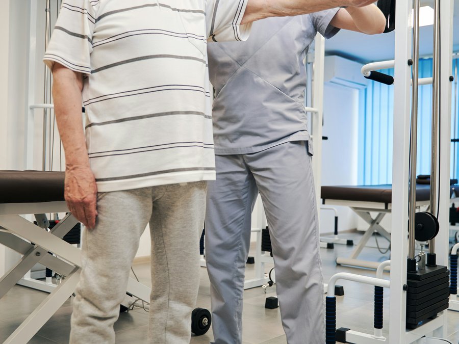 A physiotherapist guiding an older man through an arm-strengthening exercise